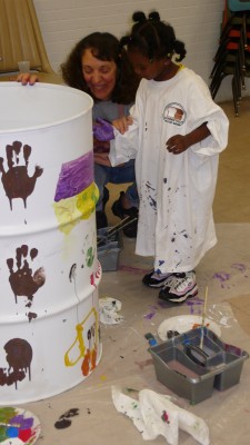 Artist Susan Rosano and a youth participant work together on oil drum art.