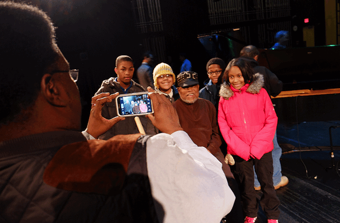 Detroit School of Arts students take a photo by smartphone with jazz legend Marcus Belgrave after a UMS school-day performance.
